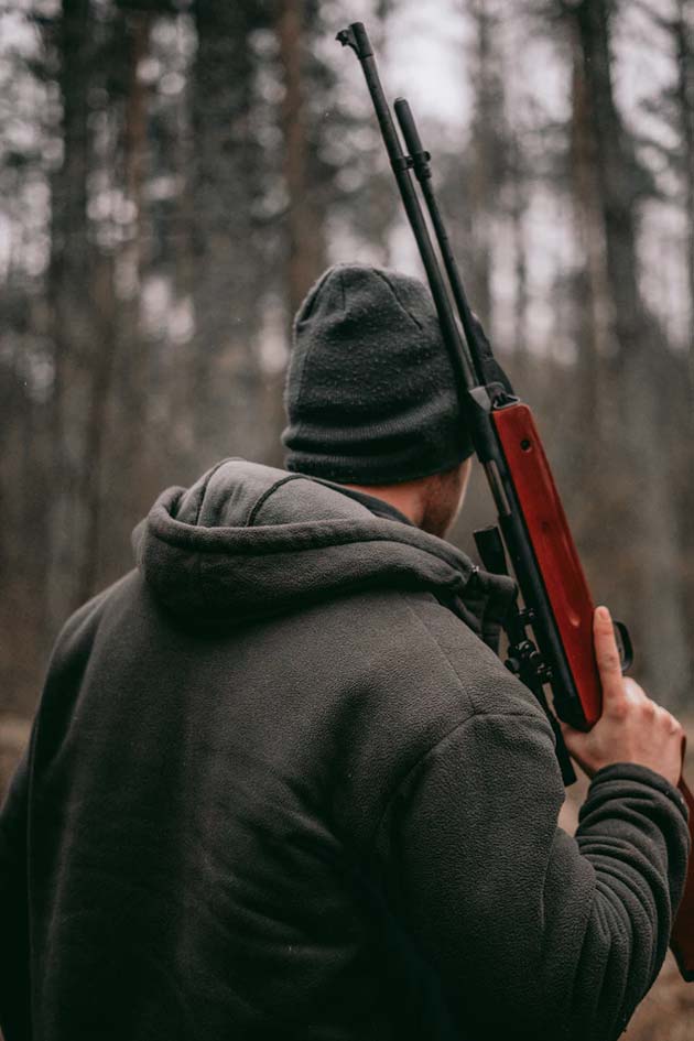 An outdoorsman holding a rifle over his shoulder