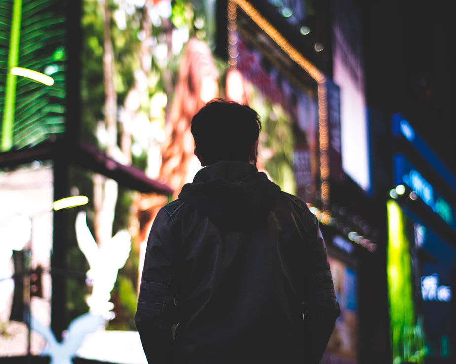 A man standing alone near city lights at night
