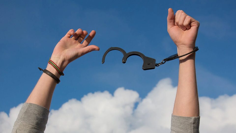 A freed person breaks out of their handcuffs.