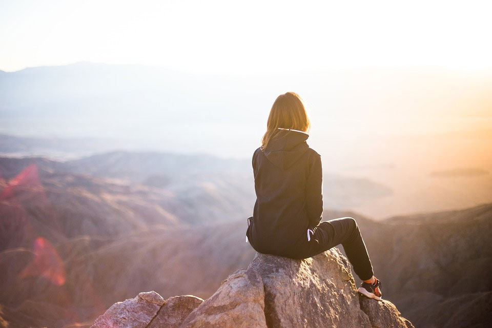 A woman sitting on top of a mountain